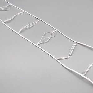 May include: A white, rectangular net-like structure with a series of interconnected squares and decorative, leaf-shaped elements. The net is made of a thin, white material, and the background is a solid gray.