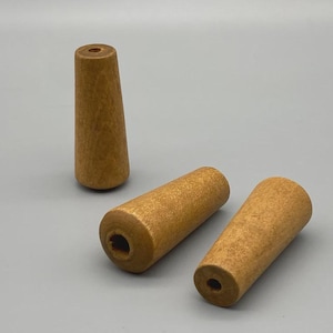 May include: Three wooden drawer pulls with a light brown finish. One pull is upright, cone-shaped, and the other two are cylindrical. Each has a hole drilled through the center for mounting. The pulls are made of wood and have a natural grain.