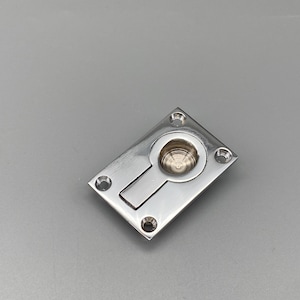 K&ouml;nnte beinhalten: Ein polierter Einbaugriff aus Edelstahl mit rechteckiger Front und kreisf&ouml;rmigem, eingelassenem Griff. Der Griff hat einen rechteckigen Schlitz und vier Schraubenl&ouml;cher. Ideal f&uuml;r Schr&auml;nke und Schubladen.