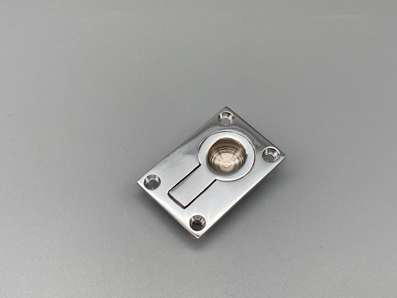 K&ouml;nnte beinhalten: Ein polierter Einbaugriff aus Edelstahl mit rechteckiger Front und kreisf&ouml;rmigem, eingelassenem Griff. Der Griff hat einen rechteckigen Schlitz und vier Schraubenl&ouml;cher. Ideal f&uuml;r Schr&auml;nke und Schubladen.