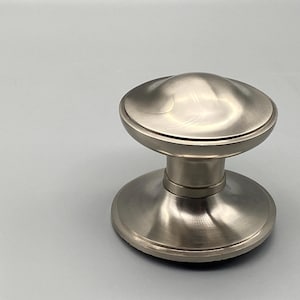 以下が含まれることがあります： 丸みを帯びた上部とベースを備えた、つや消しニッケルのドアノブ。ノブは、上部とベースを接続する円筒形のステムを備えています。このハードウェアは室内ドア用に設計されており、モダンな美しさを持っています。