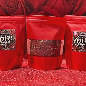 May include: Three red pouches of "Enchanted Love Powder" with a clear window on one. Each pouch has a label with the words "Love Powder" in an elegant script, surrounded by roses. The background features red roses.