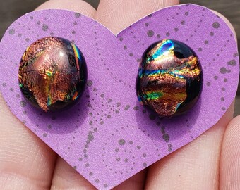 May include: A pair of iridescent glass earrings with a copper and black colour scheme. The earrings are displayed on a purple heart-shaped card.