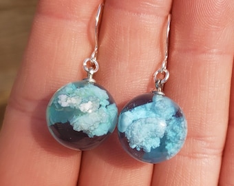 Pendientes de resina Nubes y Cielo Azul: Esfera de resina de cielo azul brillante y soleado con esponjosas nubes blancas en su interior, engarzada en alambres rellenos de plata de ley.