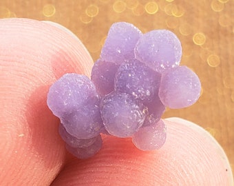 Op de afbeelding: Een cluster van paarse agaat, ook wel geode genoemd, met een glad, afgerond oppervlak. De agaat is een natuursteen met een unieke, organische vorm.
