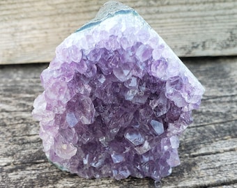 May include: A large amethyst crystal cluster with a purple and white color. The crystal is raw and has a natural, rough texture.