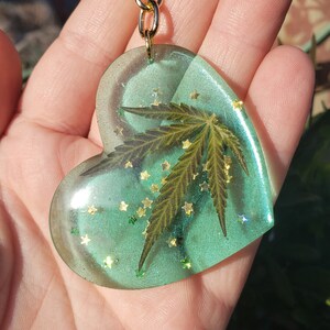 May include: A green heart-shaped resin keychain with a pressed green leaf and gold glitter inside.