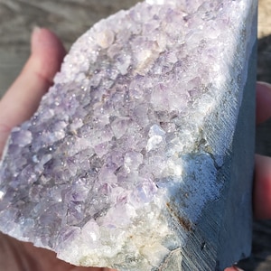 May include: A large amethyst geode with a cluster of purple crystals. The geode is raw and has a natural, rough texture.
