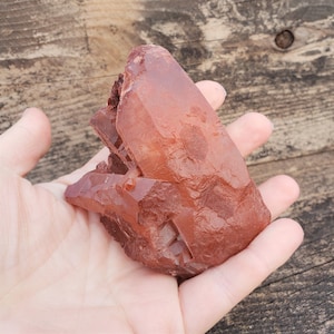 May include: A large, red, crystal cluster with a clear, glassy texture. The crystal is in the shape of a point and has a rough, natural surface.