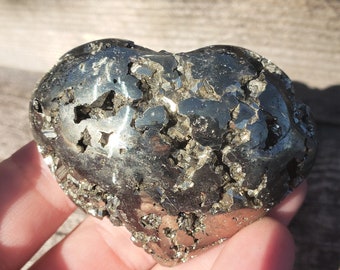 May include: A heart-shaped pyrite crystal with a rough, metallic surface. The crystal is a deep gold color and has a natural, unpolished look.