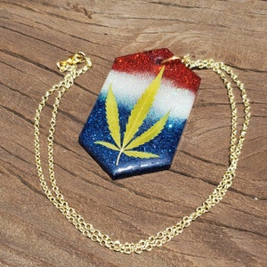 Collar de hoja de marihuana: colgante hexagonal con fondo de pigmento rojo, blanco y azul, con cadena chapada en oro.