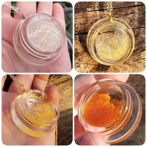 May include: Three glass pendants with gold chains. The pendants are filled with different colored glitter. The first pendant is filled with white glitter, the second with yellow glitter, and the third with orange glitter.