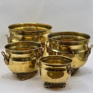 Peut inclure: Quatre jardinières antiques en laiton de tailles variées. Chaque pot a un corps arrondi, des poignées décoratives et des pieds ornés. Le laiton a une finition polie. Ces pots décoratifs conviennent à une utilisation intérieure ou extérieure.