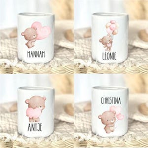 K&ouml;nnte beinhalten: Vier wei&szlig;e Keramikbecher mit Illustrationen von Teddyb&auml;ren und Namen. Jeder Becher hat ein anderes Design: ein B&auml;r, der ein Herz h&auml;lt, ein B&auml;r mit Luftballons und ein B&auml;r mit Herzen. Die Namen "Hannah", "Leonie", "Antje" und "Christina" sind aufgedruckt.