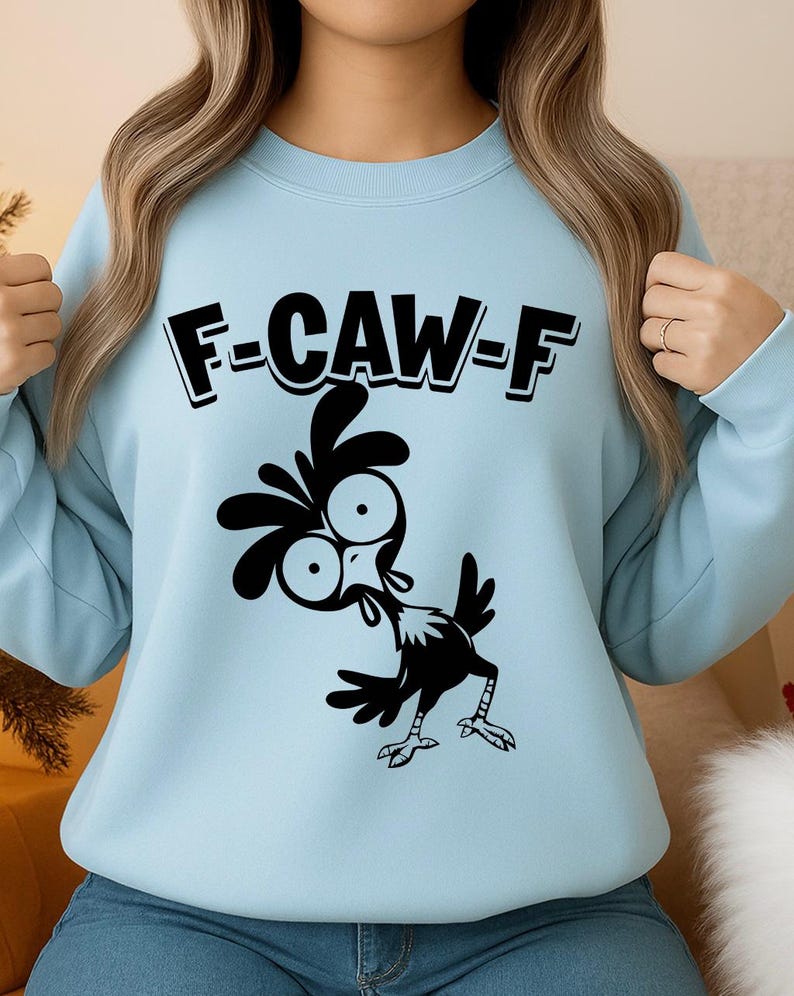 May include: Light blue sweatshirt with the text "F-CAW-F" above a black cartoon chicken illustration. The chicken has large eyes and is in a comical pose. The sweatshirt is a solid light blue color.
