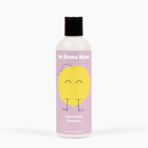 May include: A white shampoo bottle with a black cap. The label is light purple with the text "No Drama Mama" and "Chase Away Shampoo". A yellow cartoon lemon with a smiling face is on the label. The bottle contains 237 ml.