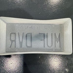 May include: A clear, rectangular stamp with the text "AVO JUM" in large, bold letters. Above the text is the word "CALIFORNIA" in smaller, reversed letters. The stamp is set in a rectangular frame.
