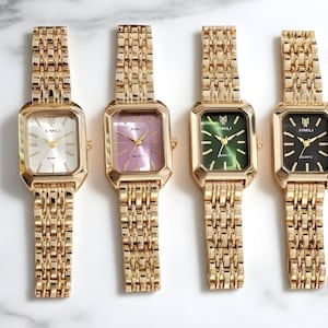 May include: Four gold-toned rectangular watches with matching link bands. Each watch face has a different color: white, pink, green, and black. The watch faces have the text "XIMILI" and "QUARTZ".