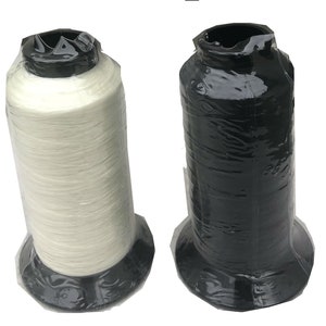 May include: Two spools of thread, one white and one black, are wrapped in clear plastic and have black bases.