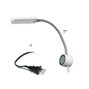 May include: A white LED desk lamp with a flexible, silver-colored gooseneck. The lamp head is 7 inches long and has a black power cord with a US plug. The lamp base is white and round.