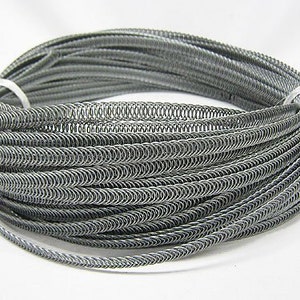 May include: A coil of silver-colored metal wire, wound in a tight spiral, creating a decorative trim or edging. The wire is flexible and can be used for various crafting projects.