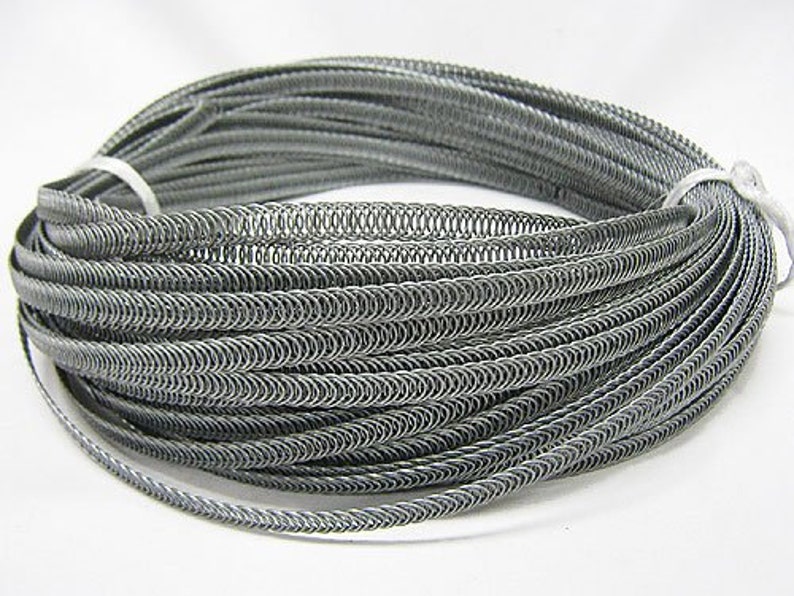 May include: A coil of silver-colored metal wire, wound in a tight spiral, creating a decorative trim or edging. The wire is flexible and can be used for various crafting projects.