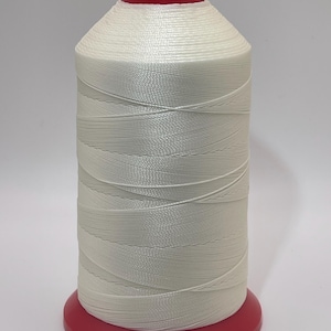 May include: A large spool of white thread wound tightly around a cylindrical core. The spool features a bright red plastic base and a matching red plastic top cap, providing a clear contrast against the smooth, white synthetic thread texture.