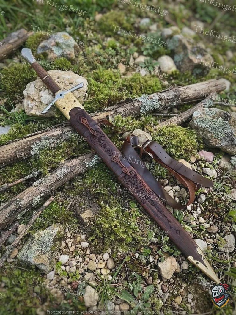 May include: A sword with a brown leather-wrapped handle and a silver-colored crossguard. The sword is housed in a dark brown leather scabbard featuring intricate embossed knotwork patterns, brass-colored metal accents, and a leather strap.