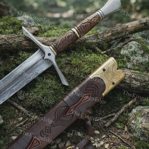 May include: A sword with a patterned steel blade, a brown carved wooden handle, and a silver pommel. Beside it lies a matching brown wooden scabbard featuring intricate carvings and a brass-colored metal throat piece with a leather strap.