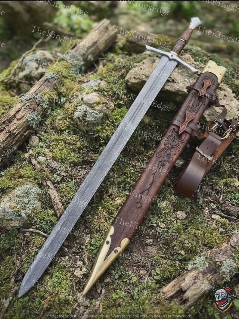 May include: A longsword with a patterned Damascus steel blade, a silver-toned crossguard, and a dark wooden grip. The matching wooden scabbard features intricate carvings, brass fittings at the tip and throat, and an attached brown leather belt.