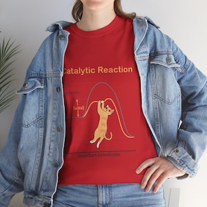 以下が含まれることがあります： 「Catalytic Reaction」の文字と猫のイラストが描かれた赤いTシャツ。猫はオレンジと白で、曲線からぶら下がっています。シャツにはラベル付きのグラフも表示されています。