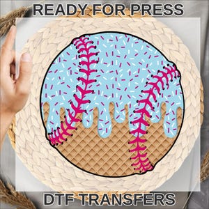 May include: A baseball-themed design featuring a light blue baseball with pink stitching and sprinkles, set against a waffle-textured background. The design includes the text "READY FOR PRESS" and "DTF TRANSFERS".