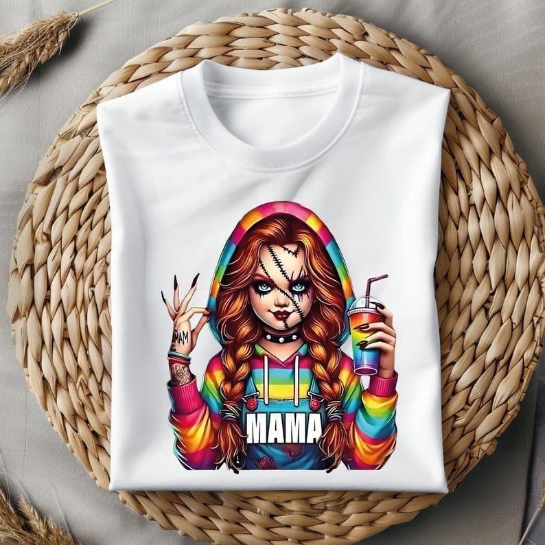 May include: White hooded sweatshirt featuring a colorful graphic of a doll-like character with stitched scars, holding a rainbow drink. The character has red hair in braids and the word "MAMA" is printed on the front.