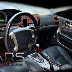 Può includere: Interni auto con sedile in pelle nera, volante e cruscotto. Il cruscotto presenta inserti in legno e indicatori. Il testo "MARS cockpit design" è visibile nell'angolo in basso a sinistra.