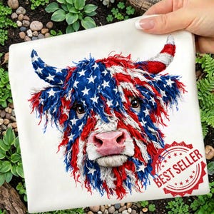 May include: A white square pillow featuring a Highland cow design. The cow's fur is colored with red and blue stripes and white stars, resembling the American flag. The pillow has a red "BEST SELLER" stamp.