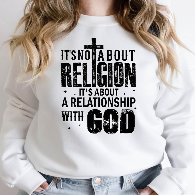 K&ouml;nnte beinhalten: Wei&szlig;es Sweatshirt mit dem schwarzen Text "IT'S NOT ABOUT RELIGION, IT'S ABOUT A RELATIONSHIP WITH GOD", mit einem Kreuz &uuml;ber dem Wort "RELIGION". Das Sweatshirt hat einen l&auml;ssigen Stil.