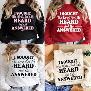 Puede incluir: Cuatro sudaderas en diferentes colores: negro, rojo, blanco y crema. Cada sudadera tiene el texto "I SOUGHT The Lord And He +HEARD+ And He ANSWERED" en un color contrastante. Las sudaderas son exhibidas en una persona.