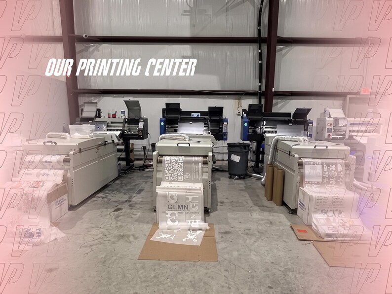 May include: Three industrial printing machines arranged in a row within a facility. Each machine features a light gray housing and is actively processing rolls of white film with printed graphics and text, including the letters GLMN and a QR code.