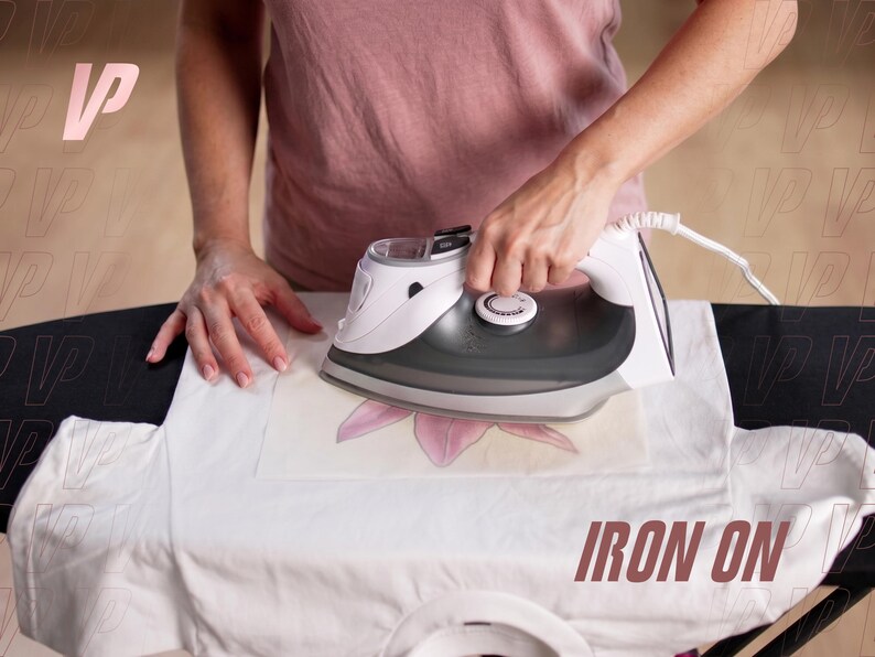 May include: A white electric iron with a dark gray soleplate is being used to press a transfer onto a white t-shirt. The iron features a temperature control dial on top and a white power cord. The text IRON ON is visible in the bottom right corner.