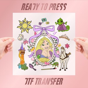 May include: A DTF transfer sheet featuring the text READY TO PRESS and DTF TRANSFER. The design includes a central oval portrait of a blonde character in a pearl frame with a purple bow, surrounded by a sun, tower, horse, chameleon, and art tools.