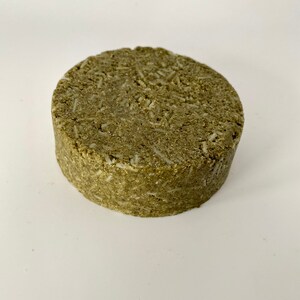 May include: A round, green and white solid shampoo bar.