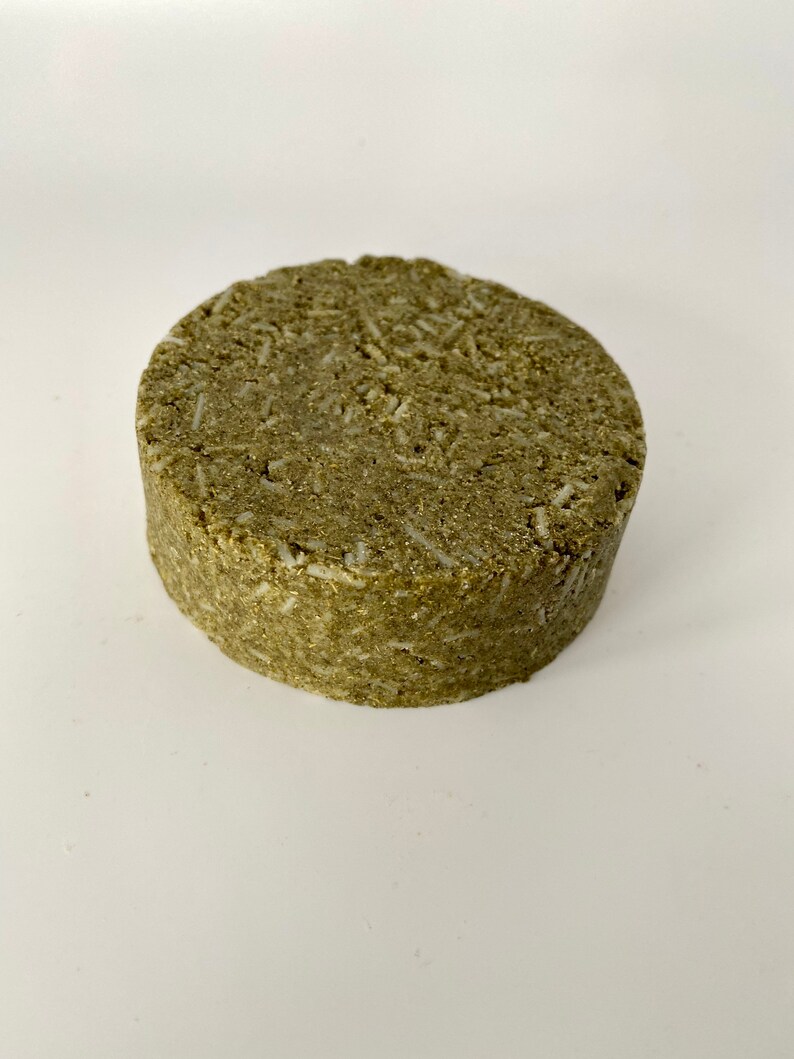 May include: A round, green and white solid shampoo bar.
