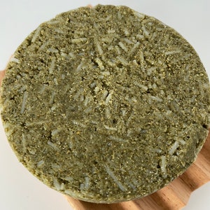May include: A round, green and white solid shampoo bar with a textured surface.