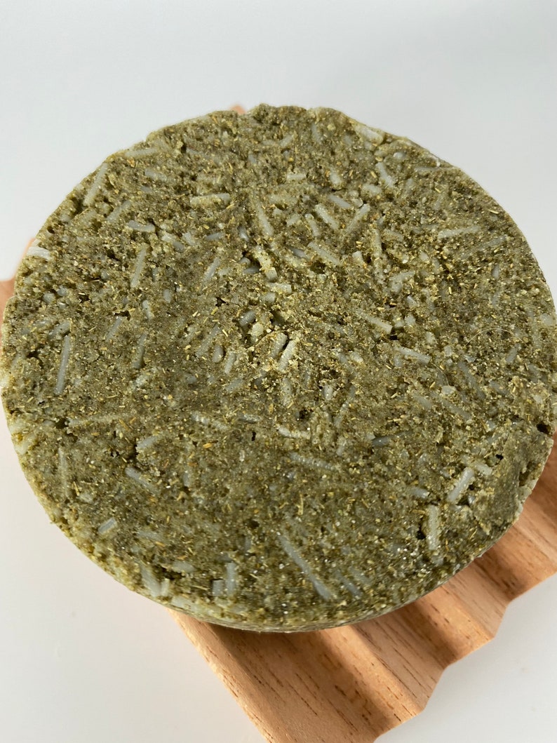 May include: A round, green and white solid shampoo bar with a textured surface.