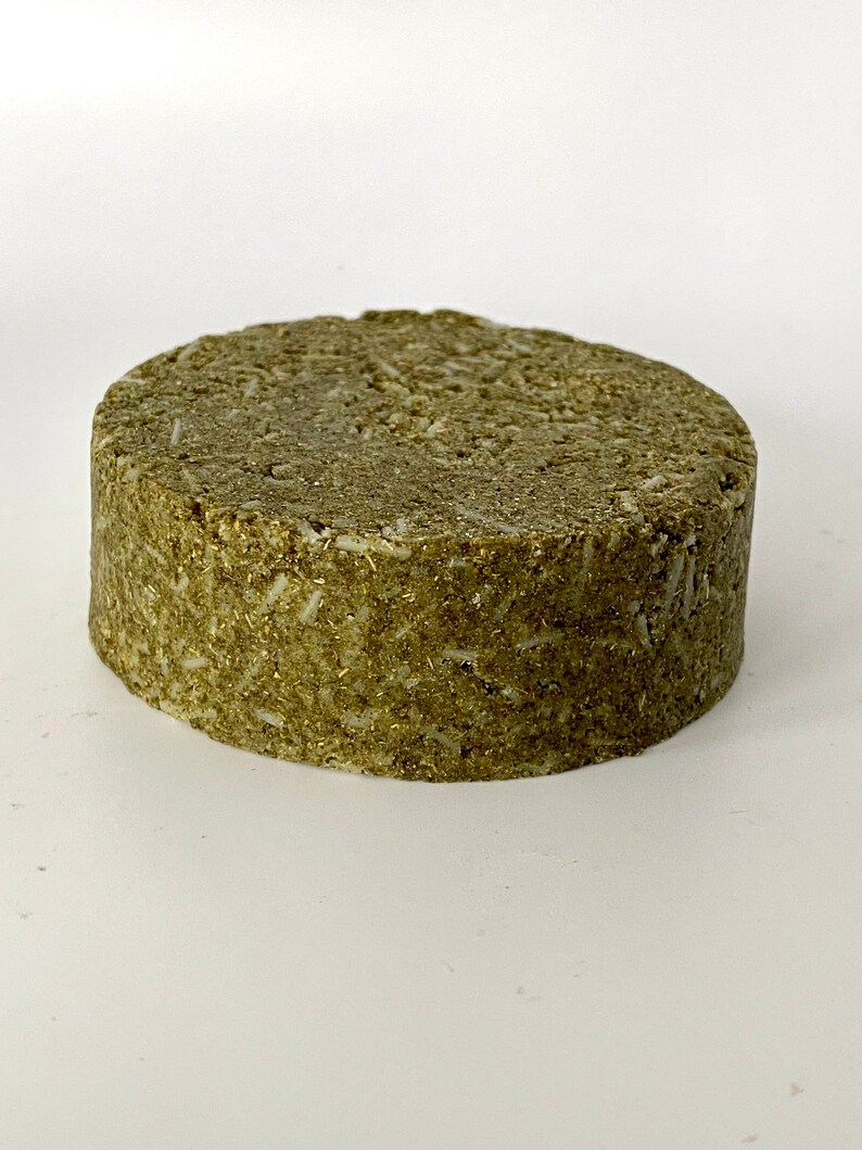 May include: A round, green, solid bar of soap. The soap has a rough, textured surface.