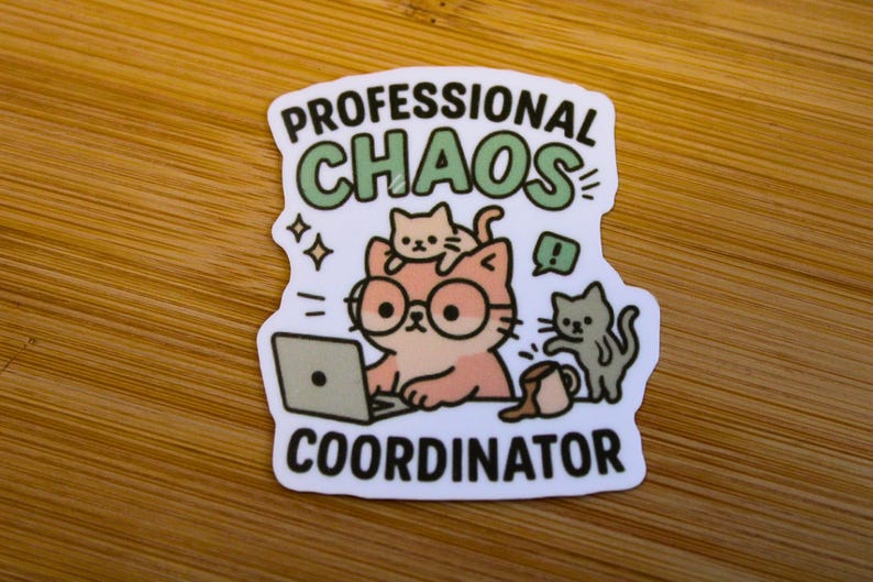 Puede incluir: Una pegatina con las palabras "PROFESSIONAL CHAOS COORDINATOR" y un gato de dibujos animados con gafas trabajando en un port&aacute;til. Tambi&eacute;n aparecen otros dos gatos en el dise&ntilde;o.