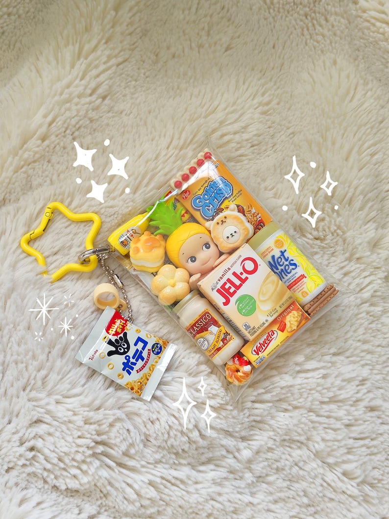 May include: A clear, rectangular pouch filled with miniature food items and figurines. Includes a small bag of popcorn, a bottle of yogurt, a box of Jell-O, and other snacks. A yellow star-shaped keychain is attached to the pouch.