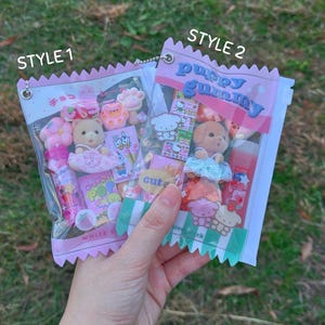 May include: Two clear plastic bags filled with assorted pink and white candies, small toys, and treats. One bag is labeled "STYLE 1" and the other "STYLE 2". The "STYLE 2" bag has the text "puppy gummy" on it.