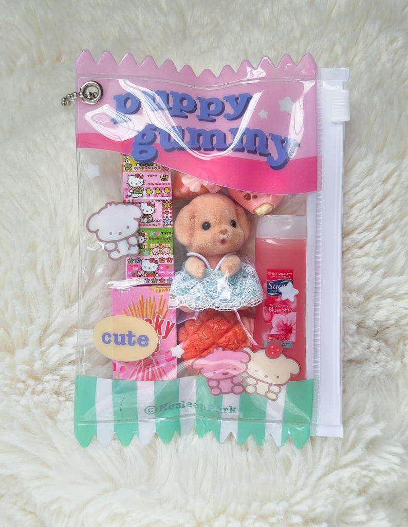 May include: A clear plastic bag with a pink top and a green and white striped bottom, filled with various items. The bag contains a puppy doll, candies, and a bottle of liquid. The text "Puppy Gummy" is printed on the bag.