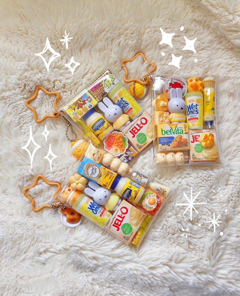 Peut inclure: Trois pochettes rectangulaires transparentes remplies de miniatures de produits alimentaires et m&eacute;nagers, incluant des bo&icirc;tes de Jell-O, de la mayonnaise Hellmann's, des lingettes Wet Ones et des figurines Miffy. Chaque pochette a un mousqueton en &eacute;toile jaune.